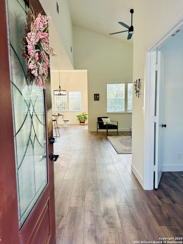 corridor with hardwood / wood-style flooring and high vaulted ceiling