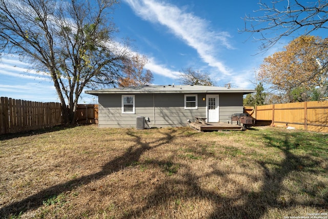 back of property with a deck, central AC, and a lawn