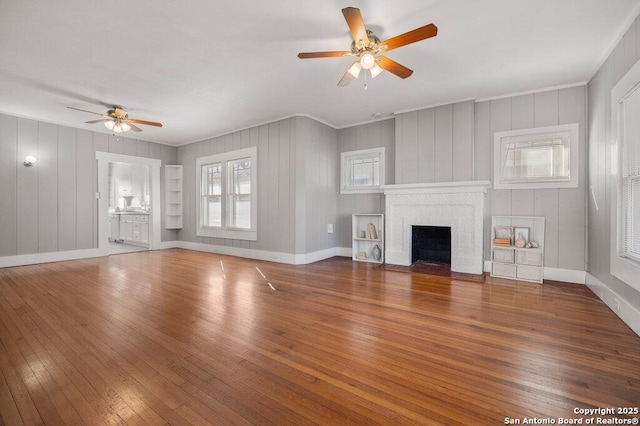 unfurnished living room featuring ceiling fan, dark wood-type flooring, and a fireplace