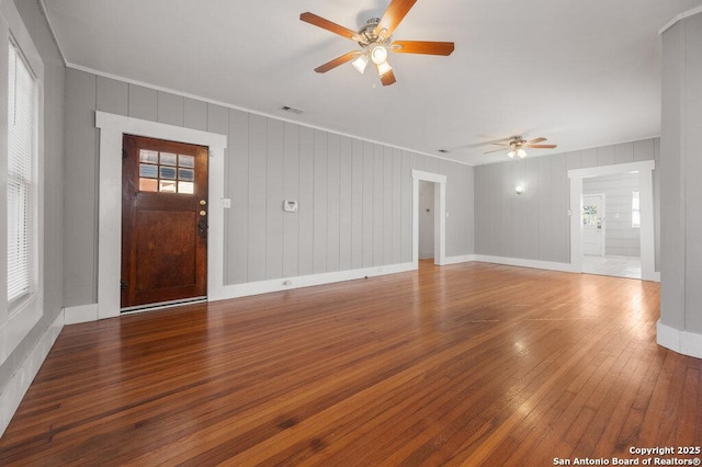 unfurnished living room with wood-type flooring, ornamental molding, and ceiling fan