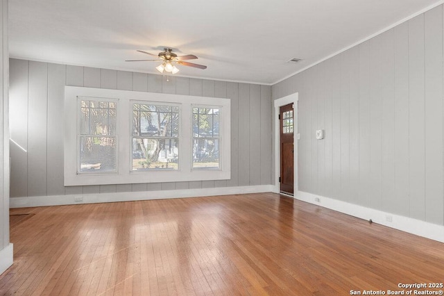 unfurnished living room featuring hardwood / wood-style floors, crown molding, and ceiling fan