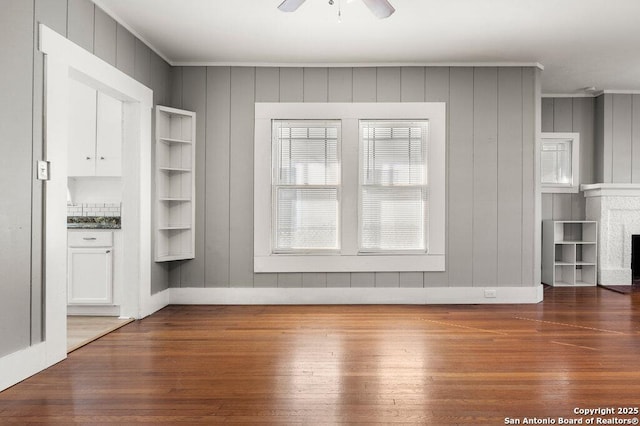 unfurnished living room with crown molding, ceiling fan, and dark hardwood / wood-style floors