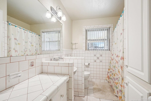 bathroom with tile walls, tile patterned floors, a wealth of natural light, and toilet