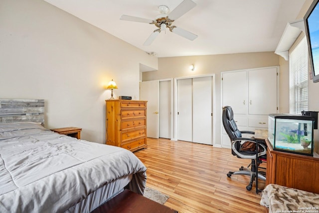 bedroom featuring ceiling fan, vaulted ceiling, multiple closets, and light hardwood / wood-style flooring