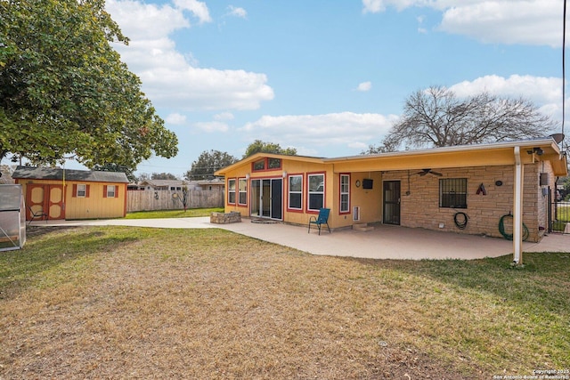 back of house with a yard, ceiling fan, a storage shed, and a patio