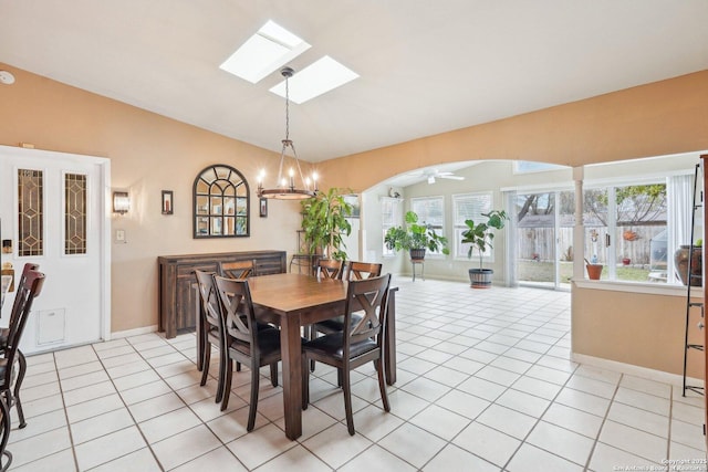 tiled dining area featuring ceiling fan with notable chandelier, a wealth of natural light, and lofted ceiling with skylight