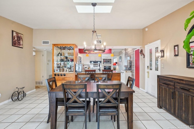 tiled dining room featuring a skylight and a chandelier