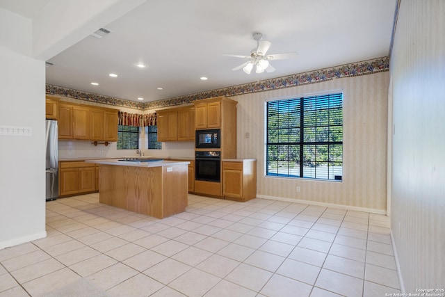 kitchen featuring black appliances, ceiling fan, a center island, and light tile patterned floors