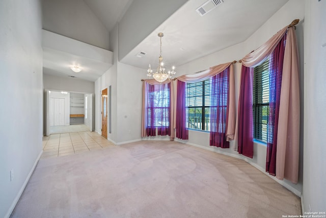 carpeted empty room featuring vaulted ceiling and an inviting chandelier