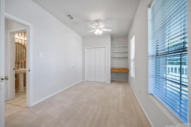 unfurnished bedroom with connected bathroom, sink, a closet, ceiling fan, and light colored carpet