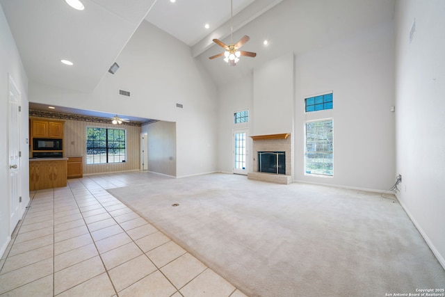 unfurnished living room with a towering ceiling, ceiling fan, and light tile patterned flooring