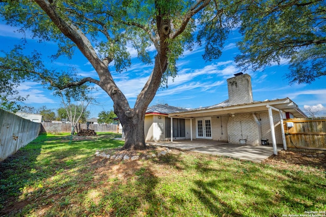 rear view of house with a patio area, a yard, and french doors