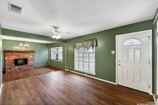 entrance foyer featuring a healthy amount of sunlight, a fireplace, dark hardwood / wood-style flooring, and ceiling fan with notable chandelier