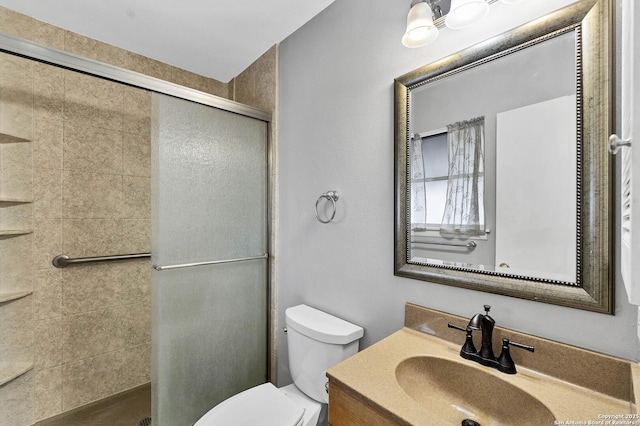 bathroom featuring a shower with shower door, vanity, and toilet