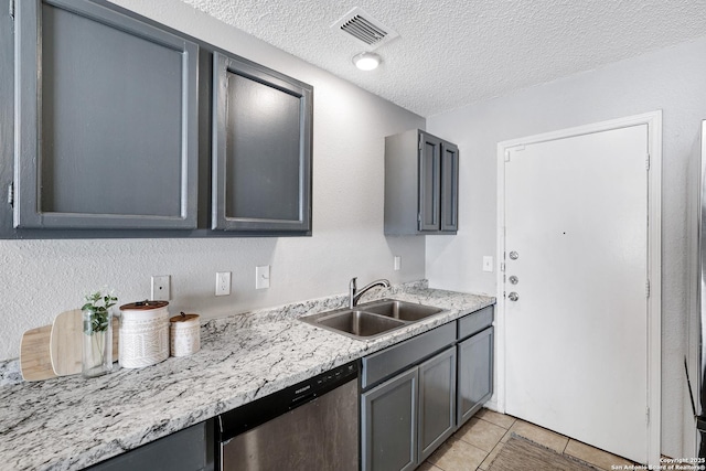 kitchen featuring a textured ceiling, gray cabinetry, stainless steel dishwasher, and sink