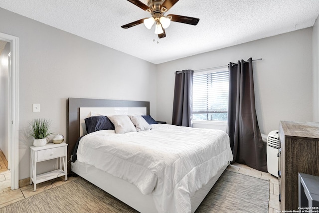 bedroom with ceiling fan, light tile patterned floors, and a textured ceiling