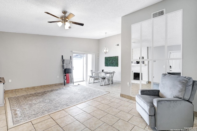 living room with a textured ceiling, ceiling fan, and light tile patterned floors