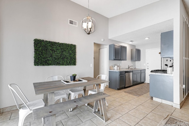 dining space featuring a high ceiling, sink, light tile patterned floors, and an inviting chandelier