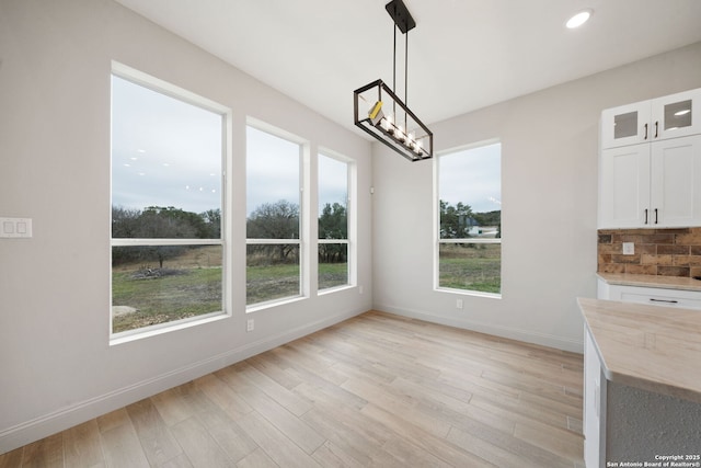 unfurnished dining area featuring light wood-type flooring and an inviting chandelier