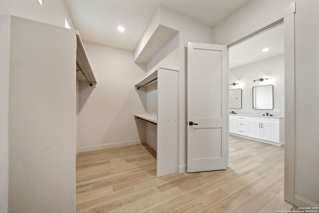 walk in closet with light hardwood / wood-style flooring and sink