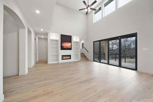 unfurnished living room featuring ceiling fan, french doors, and a towering ceiling