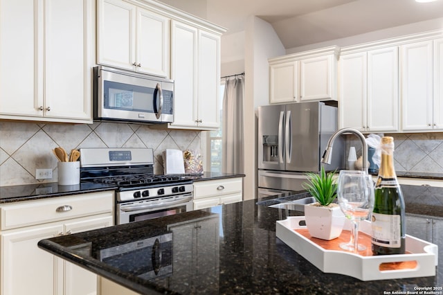 kitchen featuring appliances with stainless steel finishes, decorative backsplash, white cabinets, and dark stone counters