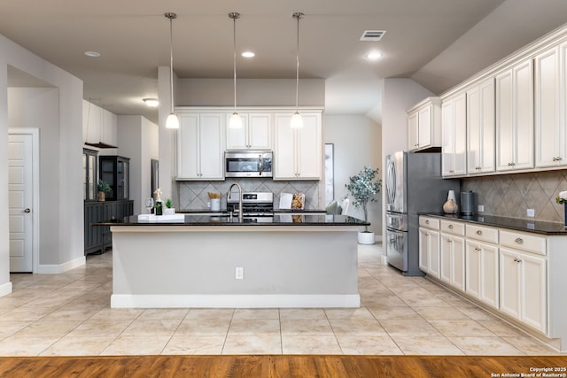 kitchen with light tile patterned floors, white cabinetry, a center island with sink, appliances with stainless steel finishes, and pendant lighting