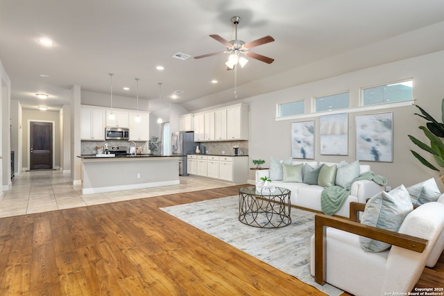 living room featuring ceiling fan, light hardwood / wood-style floors, and sink