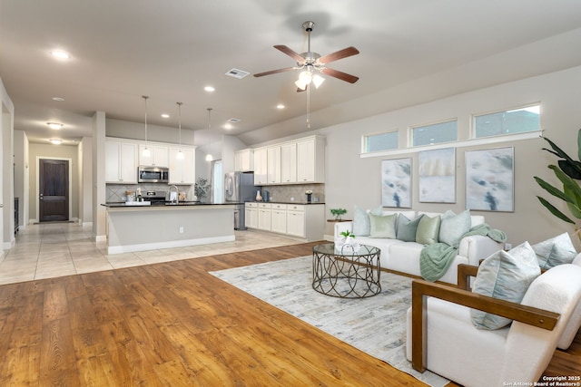 living room featuring ceiling fan, light hardwood / wood-style flooring, and sink