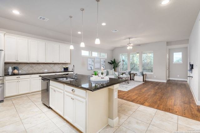 kitchen featuring appliances with stainless steel finishes, dark stone counters, sink, a kitchen island with sink, and ceiling fan