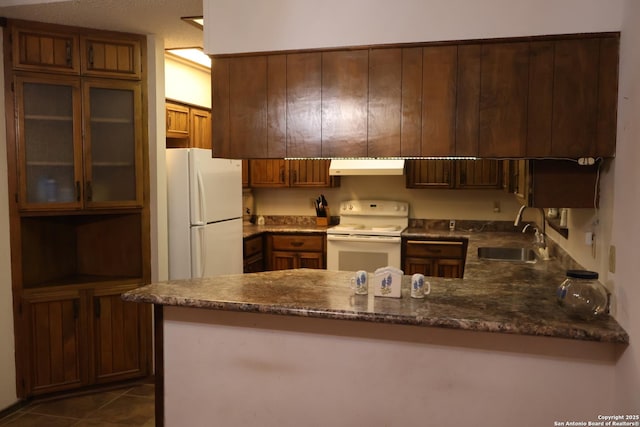 kitchen with sink, white appliances, dark tile patterned floors, and kitchen peninsula