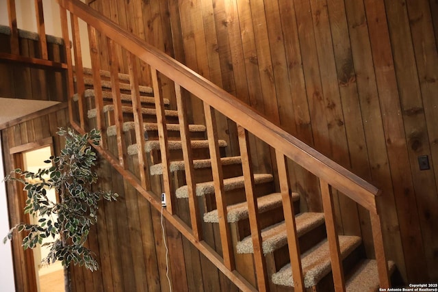 stairway featuring wood walls