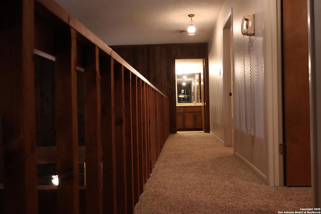 corridor with wooden walls, a textured ceiling, and carpet flooring