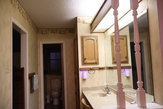 bathroom with a textured ceiling, toilet, and vanity