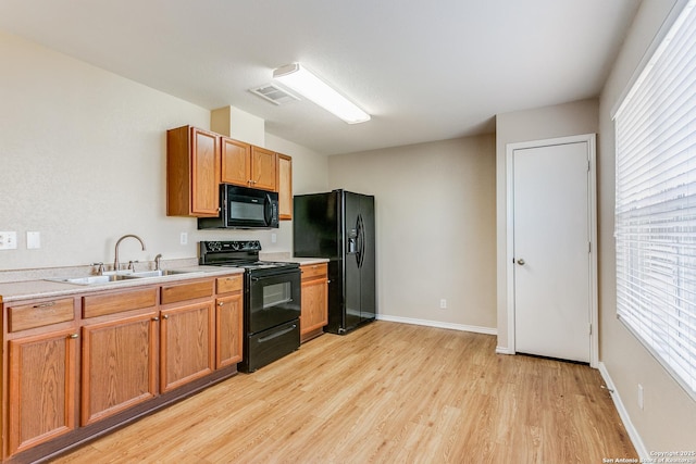 kitchen with light hardwood / wood-style floors, sink, and black appliances