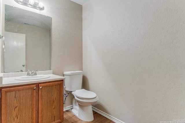 bathroom featuring wood-type flooring, toilet, and vanity