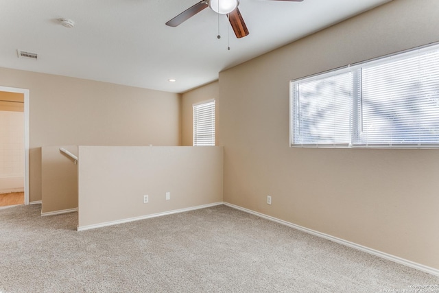 carpeted spare room featuring ceiling fan and a wealth of natural light