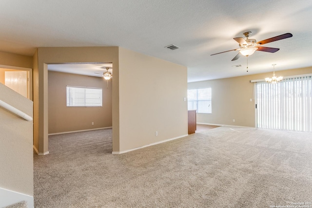 carpeted spare room with ceiling fan with notable chandelier