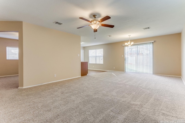 carpeted spare room featuring ceiling fan with notable chandelier