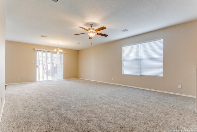 unfurnished room with a healthy amount of sunlight, ceiling fan with notable chandelier, and carpet flooring