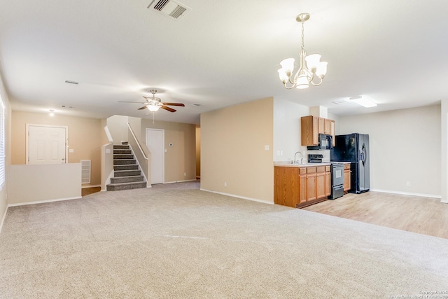 unfurnished living room with light colored carpet, ceiling fan with notable chandelier, and sink