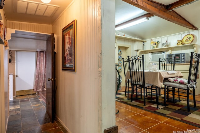 corridor featuring vaulted ceiling and wooden walls