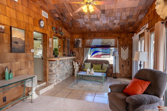 sitting room with ceiling fan, light tile patterned floors, lofted ceiling, and wooden walls