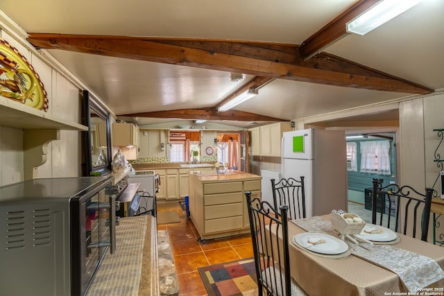 tiled dining room featuring sink and lofted ceiling with beams