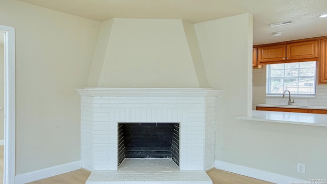 details featuring a textured ceiling, a brick fireplace, hardwood / wood-style floors, and sink