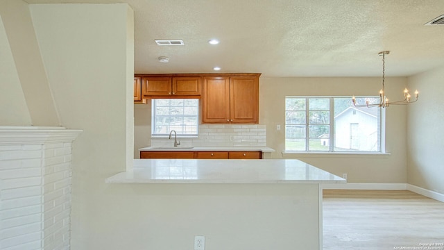 kitchen featuring decorative light fixtures, decorative backsplash, sink, an inviting chandelier, and a textured ceiling