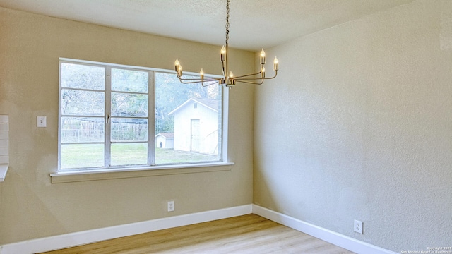 unfurnished dining area featuring an inviting chandelier and hardwood / wood-style flooring