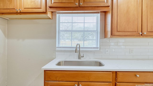 kitchen with a wealth of natural light, backsplash, and sink