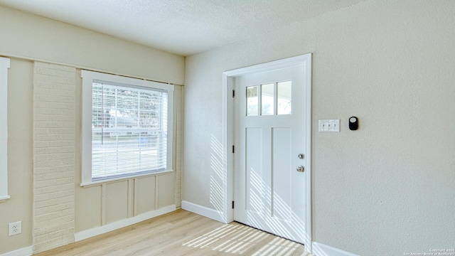 foyer entrance featuring light hardwood / wood-style floors, a textured ceiling, and a healthy amount of sunlight