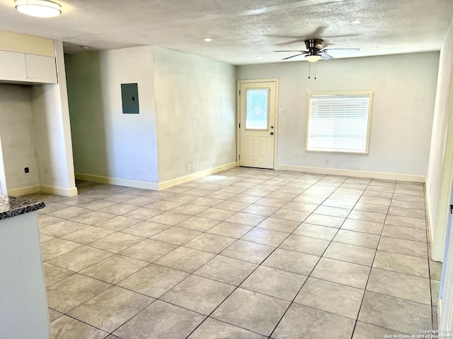 tiled spare room featuring ceiling fan, a textured ceiling, and electric panel